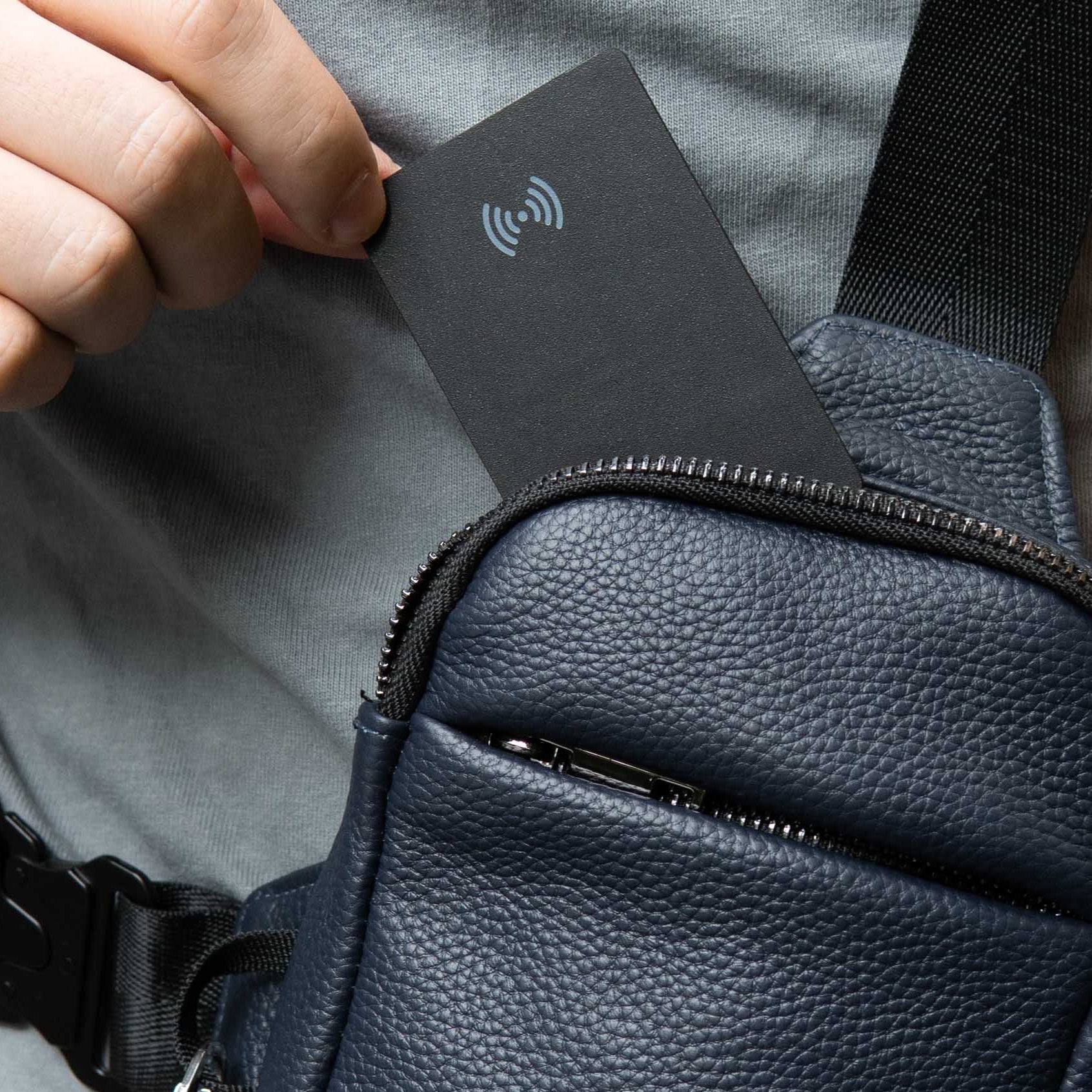 Person placing a card into a black leather bag with a textured surface.
