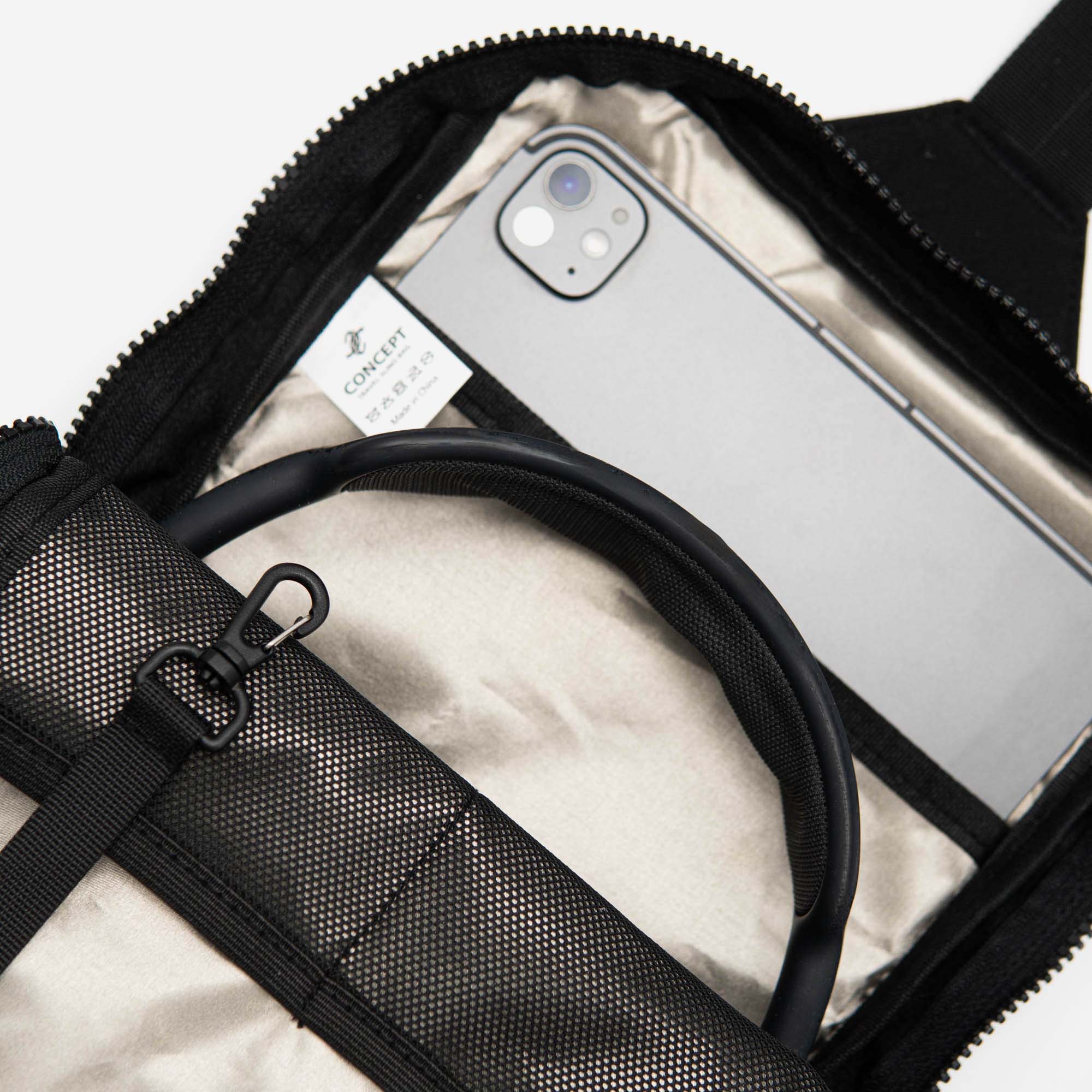 Phone and earbuds inside a black backpack with a white background